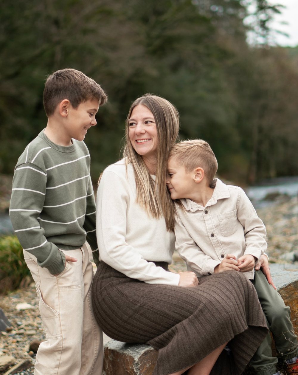 Brandy with her two sons, sitting on a rock beside a river